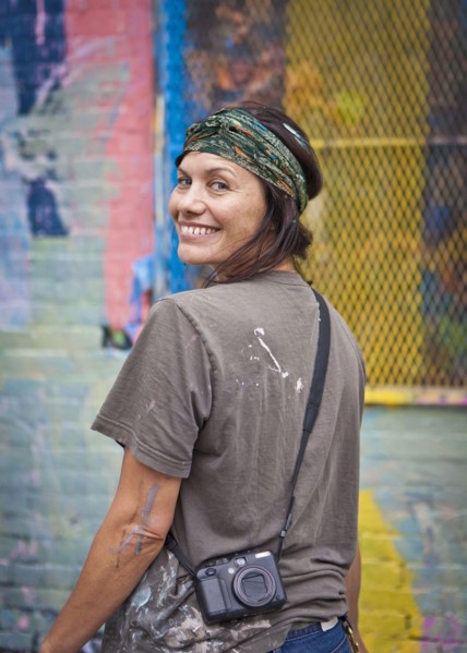 Caucasian woman with paint-splattered shirt smiling