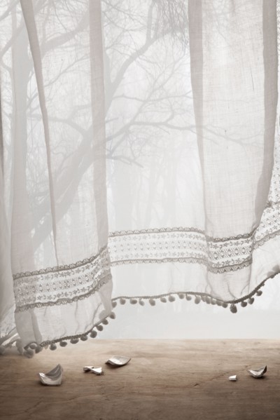 Broken ceramic shards under sheer curtains