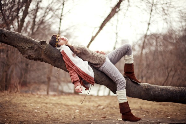 Caucasian woman laying in tree in rural field