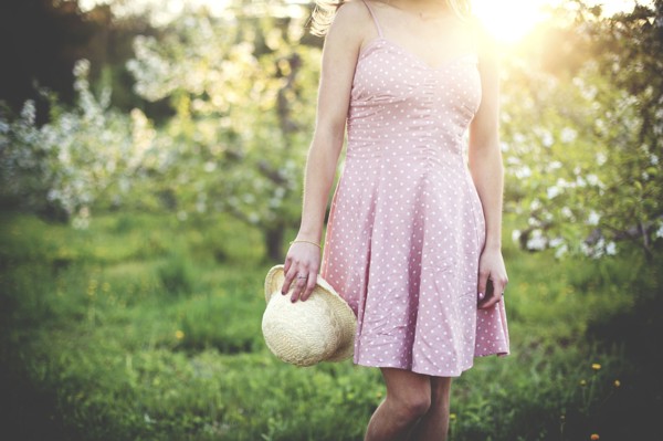 Woman holding hat in rural orchard