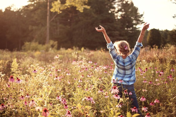 Caucasian woman cheering with arms outstretched in field