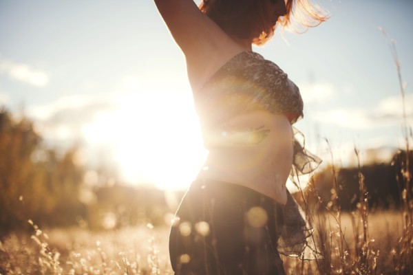 Woman dancing in tall grass in rural field