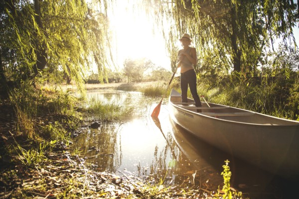 Caucasian woman rowing canoe in rural creek
