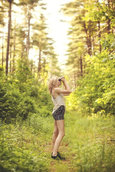 Caucasian woman using binoculars in forest