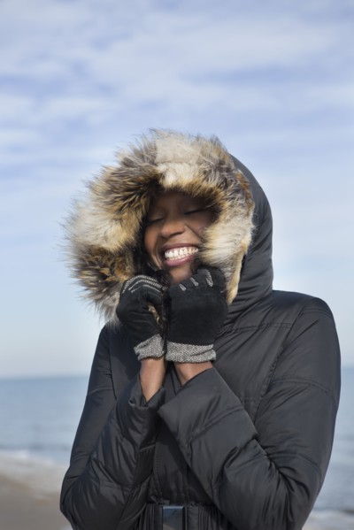 Smiling woman wearing coat on beach