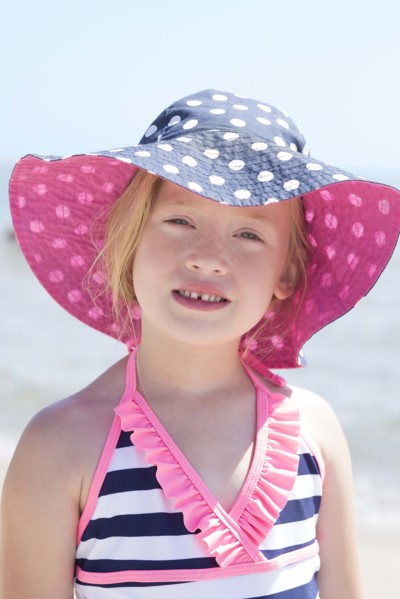 Caucasian girl wearing sun hat and bathing suit on beach