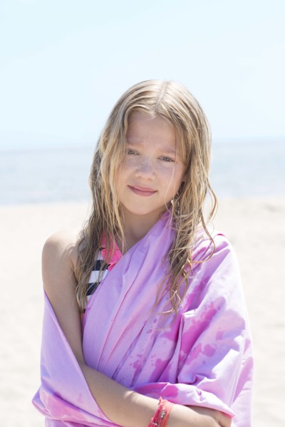 Caucasian girl wrapped in towel on beach