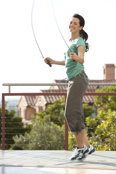 Caucasian woman jumping rope on urban rooftop