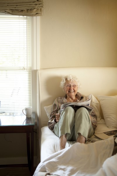 Older Caucasian woman reading newspaper in bed