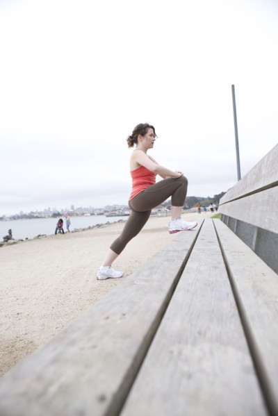 Caucasian woman stretching on beach bench