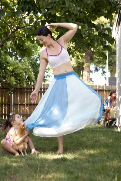 Mother and daughter dancing with chicken in backyard