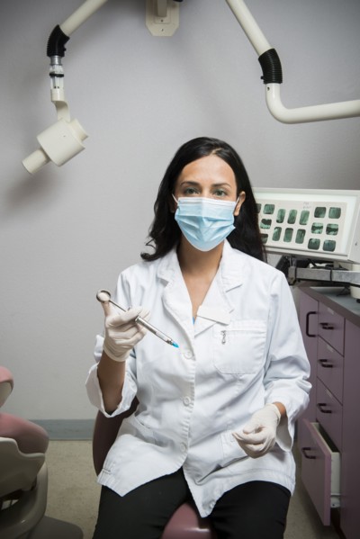 Indian dentist holding syringe in office