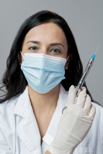 Indian dentist in surgical mask holding syringe