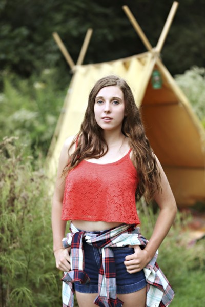 Serious woman standing at camping tent