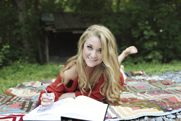 Teenage girl drawing in notebook on blanket
