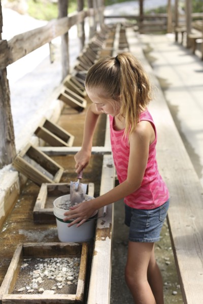 Girl shoveling rocks in bucket in trough