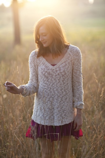 Girl standing in tall grass in rural field