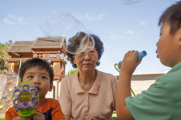 Asian grandmother and grandsons blowing bubbles outdoors