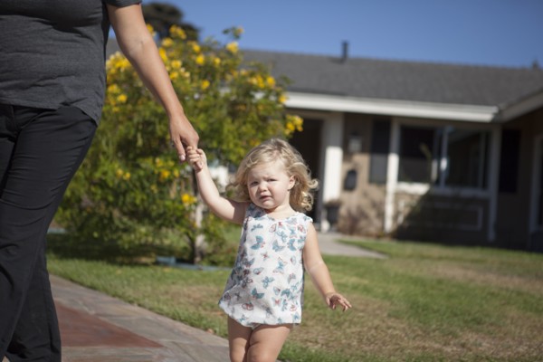 Mother and daughter walking on sidewalk