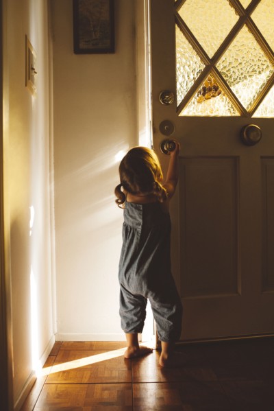 Hispanic preschooler girl opening front door