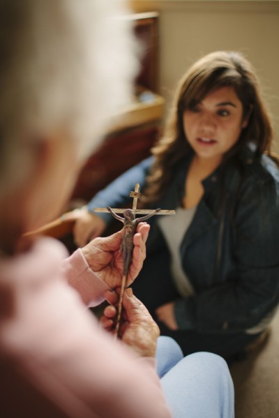 Granddaughter and grandmother praying with crucifix