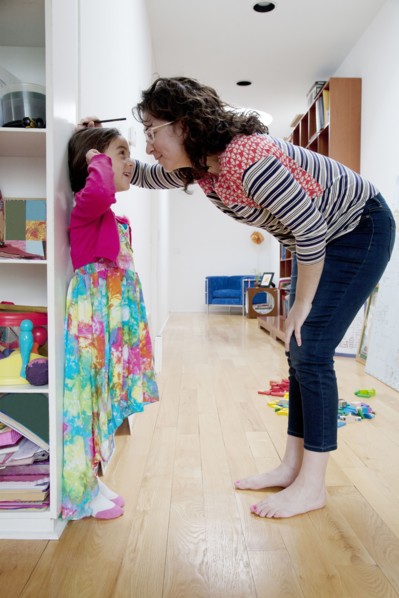Caucasian mother measuring height of daughter on wall