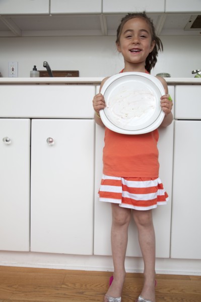 Caucasian girl holding empty plate in kitchen