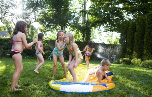 Children playing on water slide in backyard