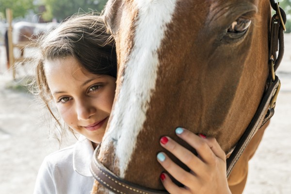 Close up of teenage girl hugging horse