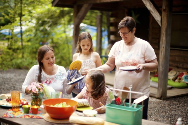 Three generations of Caucasian women cooking outside cabin