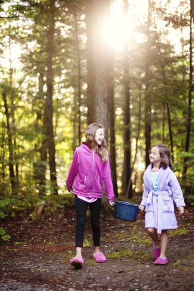 Caucasian girls carrying pot of water in forest