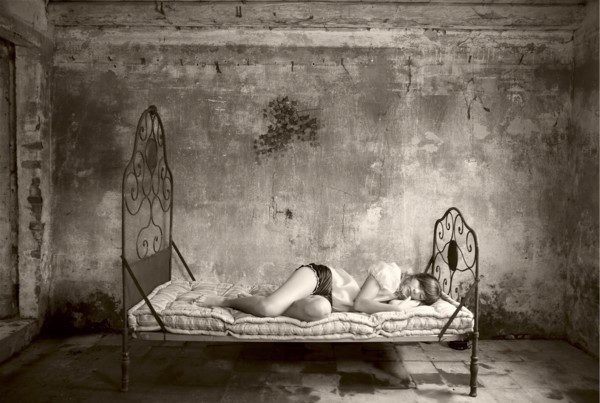 Caucasian woman laying on bed in dilapidated room