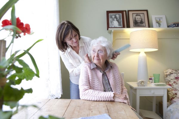Woman combing hair of elderly mother