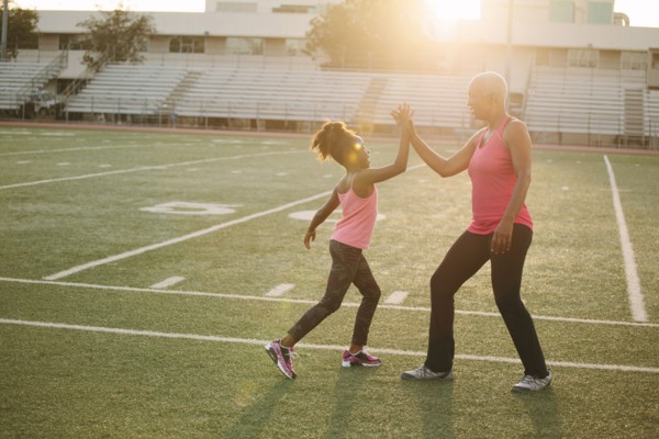 Grandmother and granddaughter high-fiving on football field