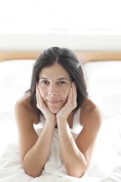 Serious Hispanic woman sitting in bed