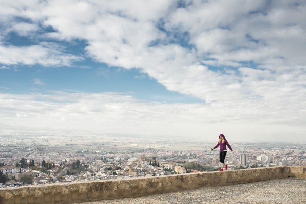 Caucasian woman on wall overlooking scenic view of cityscape