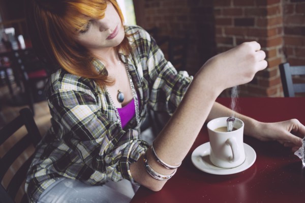Caucasian woman sprinkling sugar in coffee