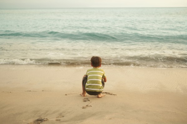 Mixed race boy squatting on beach playing