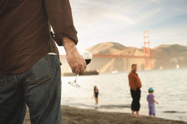 Caucasian man drinking wine on beach