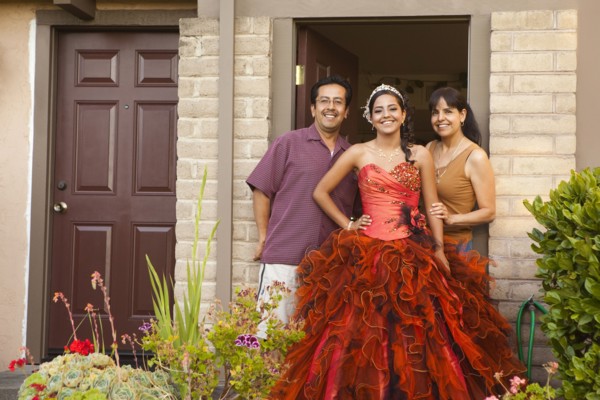 Hispanic girl dressed for quinceanera standing with parents