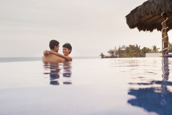 Hispanic couple hugging in swimming pool