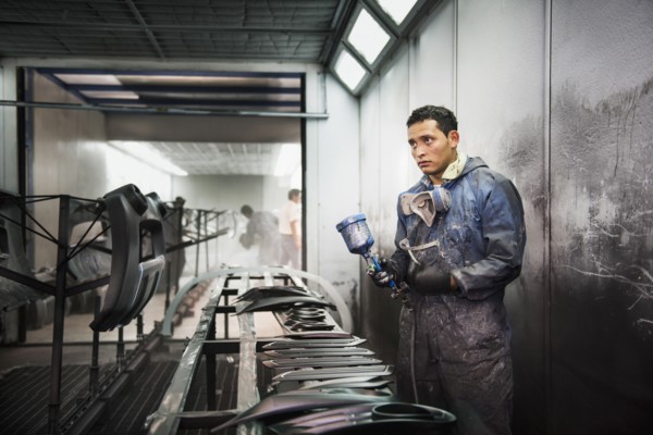 Worker spray painting in manufacturing plant