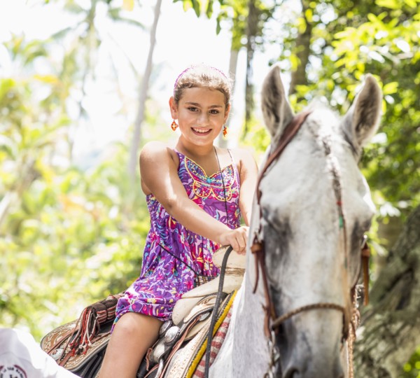 Mixed race girl riding horse in jungle