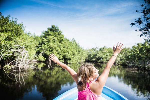 Mixed race girl sitting in canoe in still lake