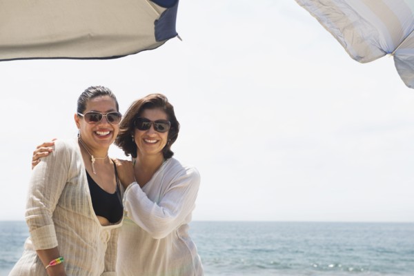 Hispanic women smiling together at beach