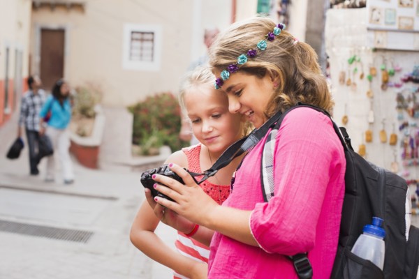Girls looking at digital camera photographs on vacation