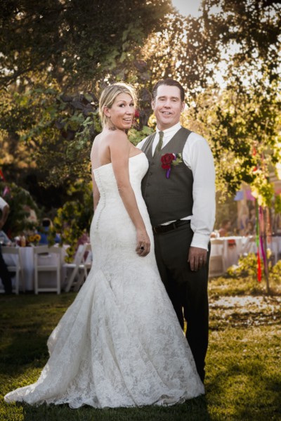 Caucasian bride and groom smiling at outdoor reception