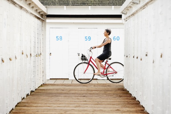 Older Caucasian woman riding bicycle on wooden dock