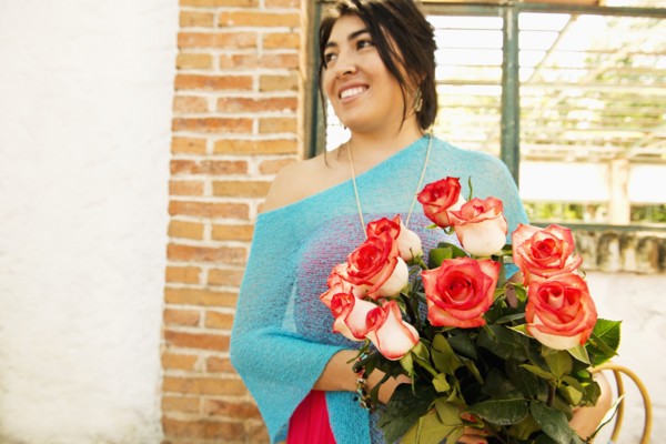 Hispanic woman carrying bouquet of roses outdoors
