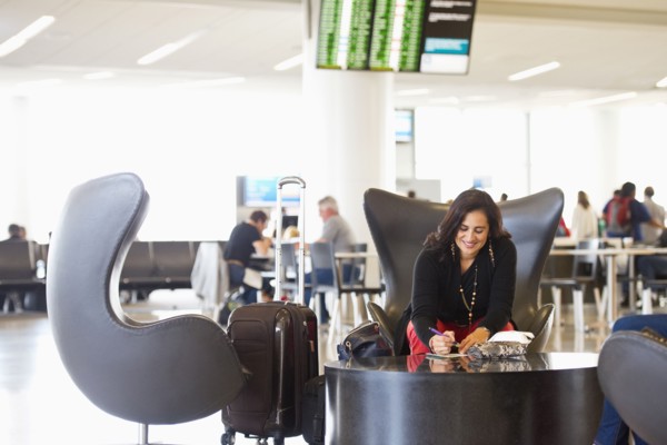 Hispanic businesswoman writing in airport waiting area